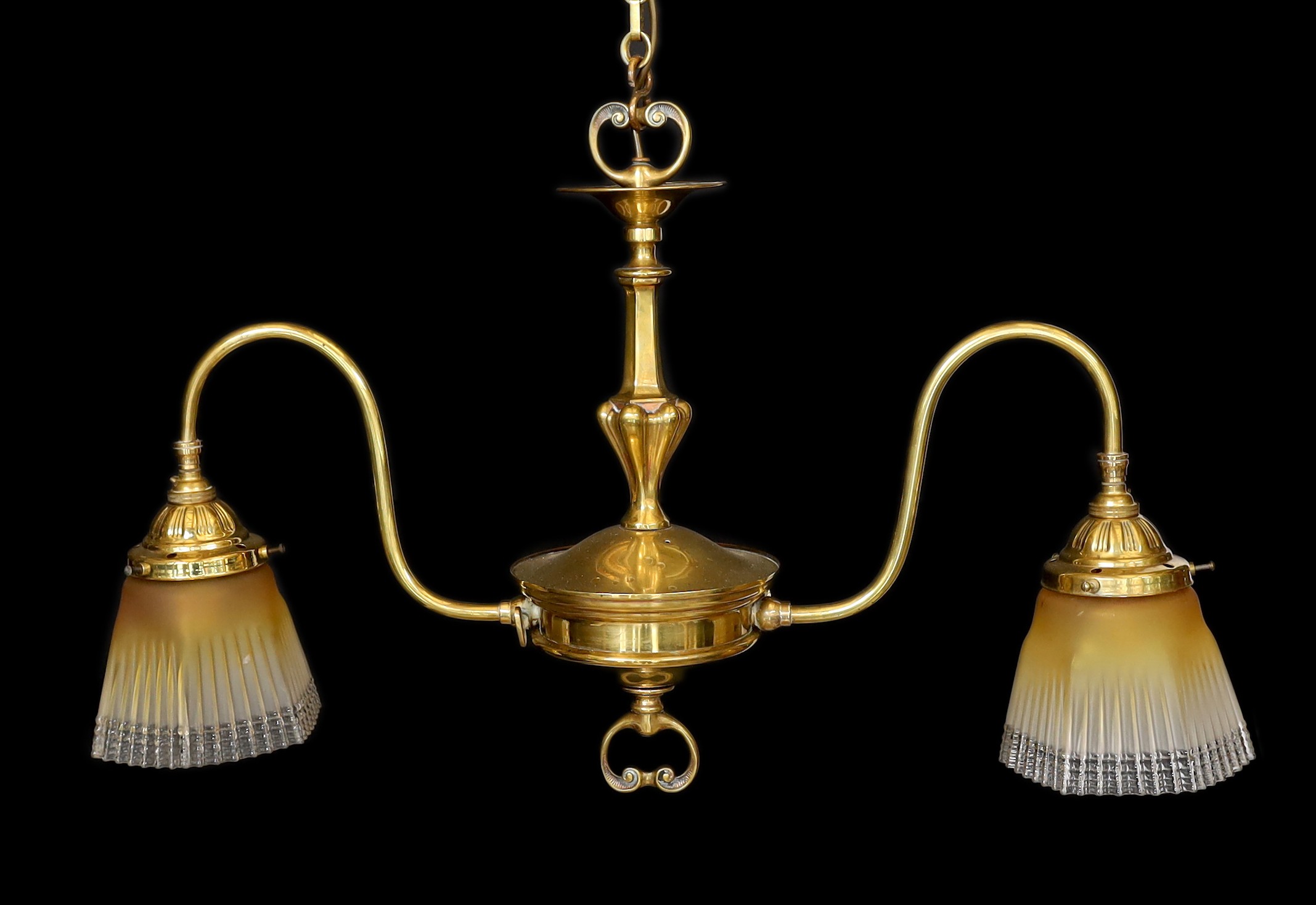An early 20th century English brass twin branch light fitting with amber tinted tall glass shades height to top of fitting 50cm, width 77cm